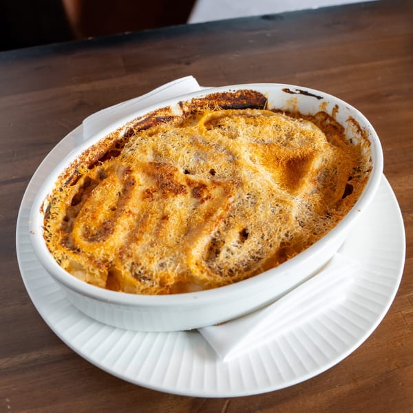 Baked Italian pasta dish with a golden-brown, crispy cheese topping in a white oval dish.