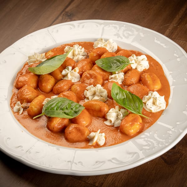 Italian gnocchi in a rich tomato sauce, garnished with fresh basil and dollops of ricotta cheese.
