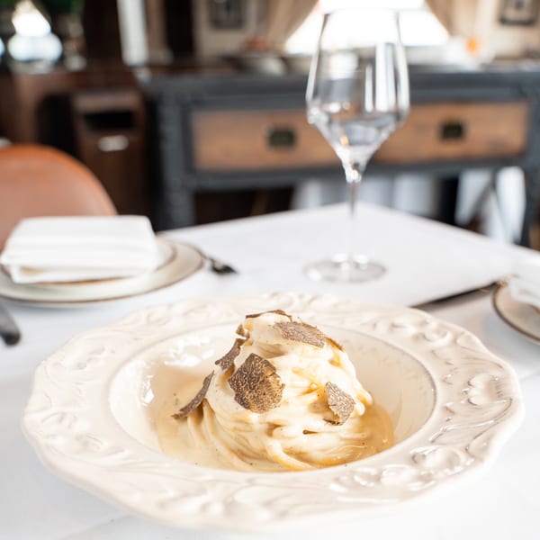 Creamy spaghetti with shaved truffles in an ornate bowl on a white tablecloth at Sicilia Mia.